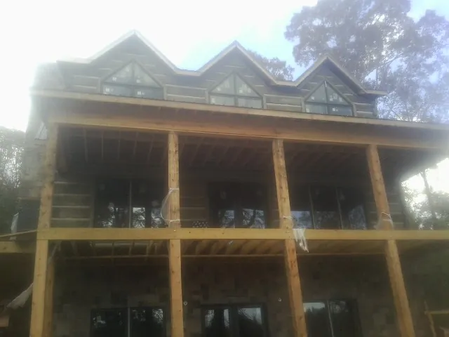 Dormers and porch framing on a large log home under construction — Roof Coating work by our crew in Chaptico