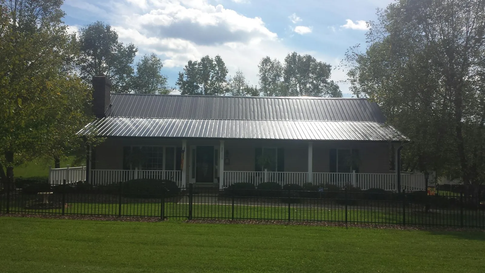 Gray metal roof on a brick ranch with a full width front porch — Gutter Guard Installation work by our crew in Chaptico