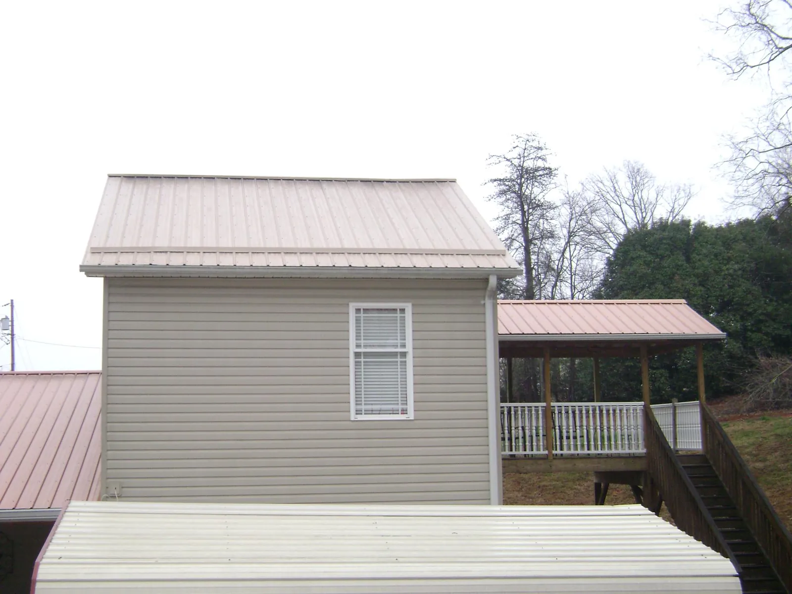 Tan metal roofs on a two story addition and attached porch, from a Roof Replacement job in Chaptico