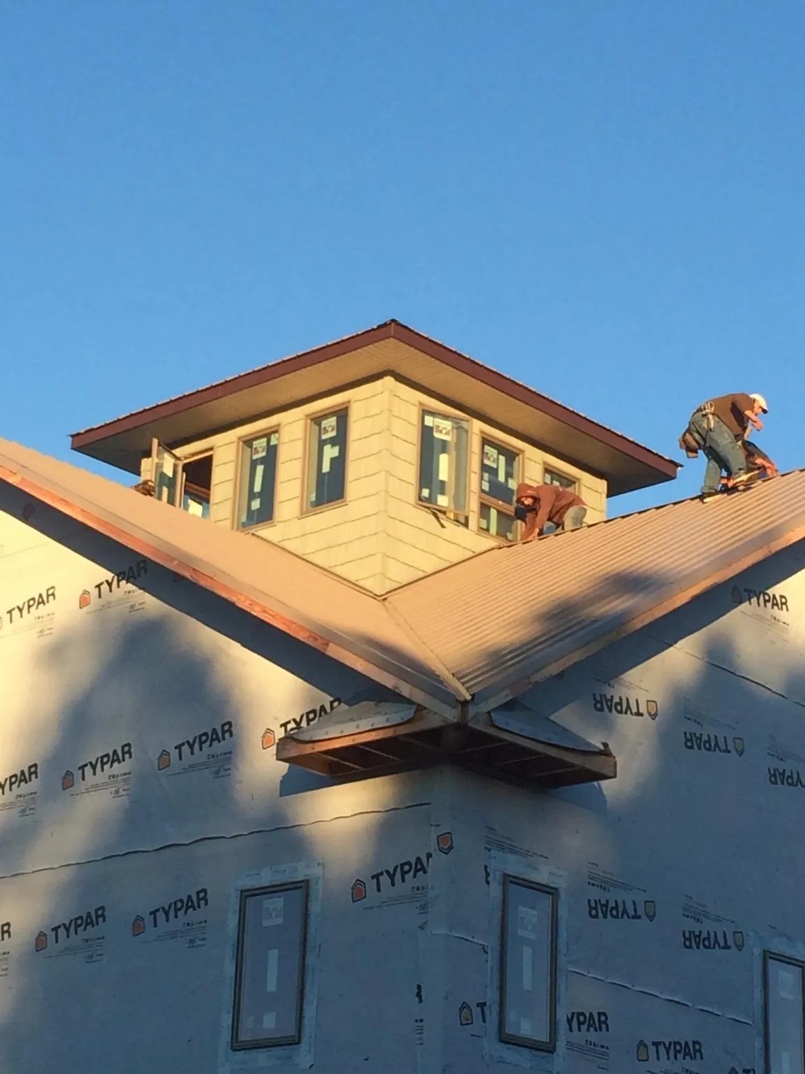 Roofers working around a rooftop cupola on a new metal roof at sunset — Roof Waterproofing in Chaptico by Roofing Brothers